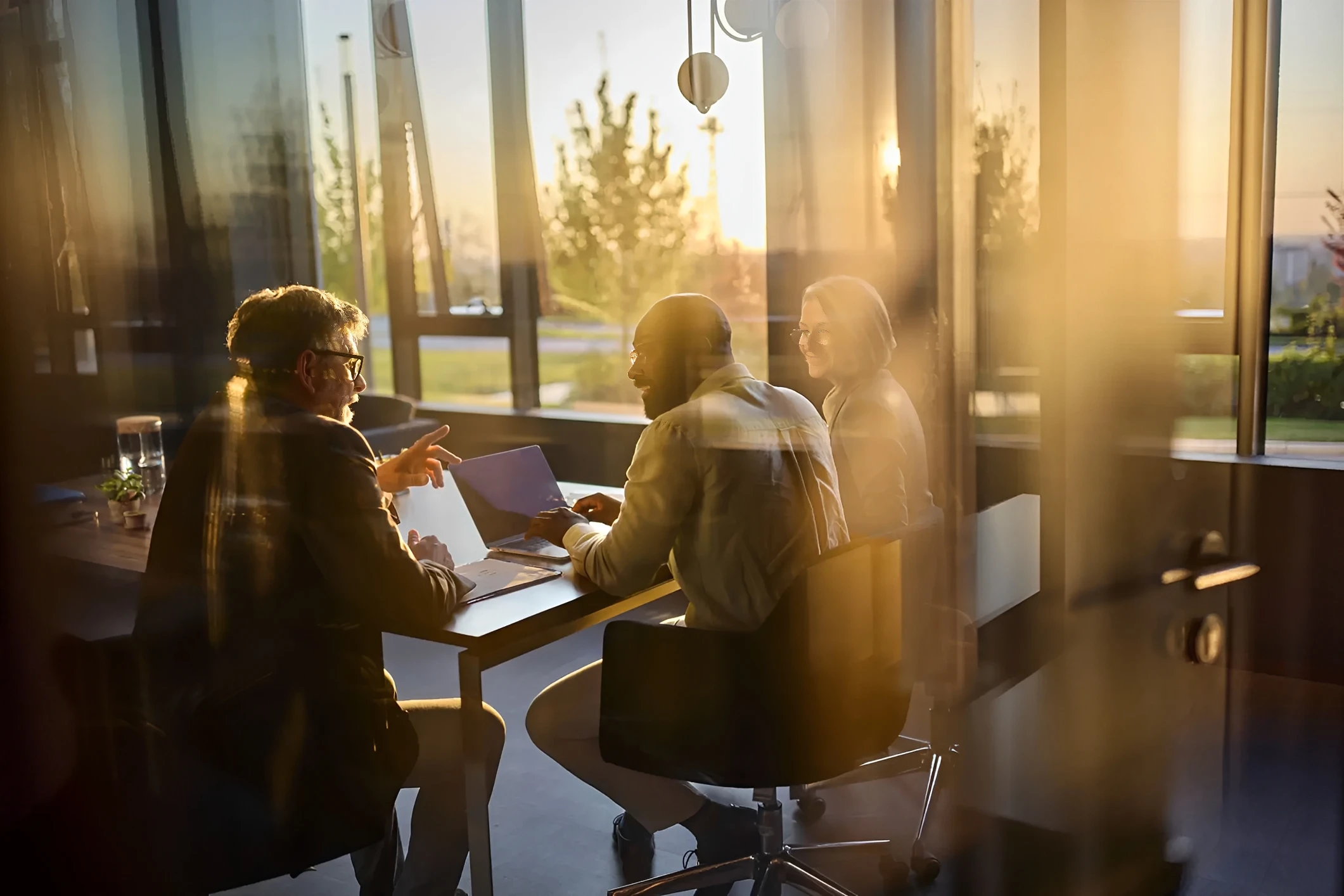 Three colleagues collaborating in a sunlit office.